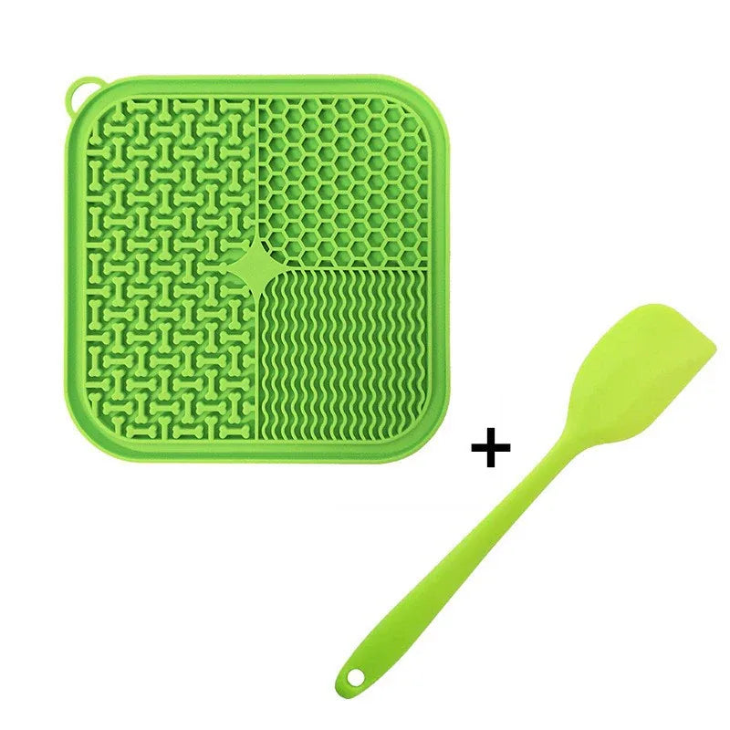 Green silicone cat lick mat with four lick textures and matching spatula, isolated on white