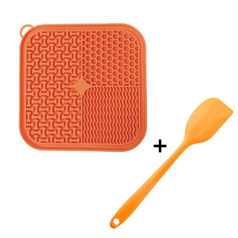 Orange silicone cat lick mat with four lick textures and matching spatula, isolated on white