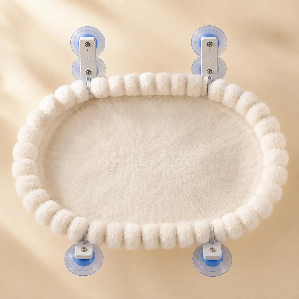 Top-down view of the oval cat window hammock showing the thick plush pad and pom-pom border