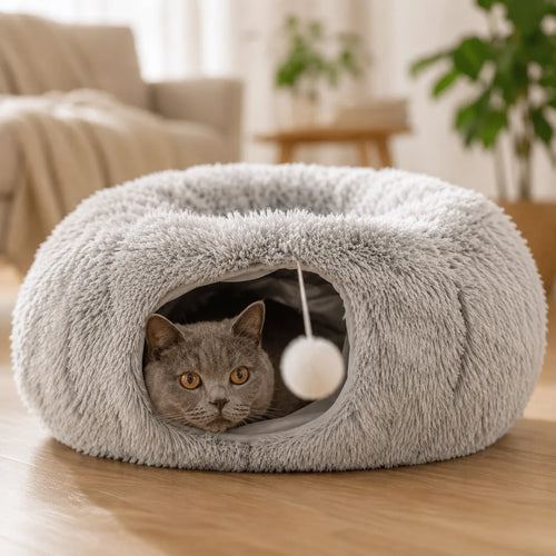 Cat peeking out of the grey plush donut tunnel bed like a burrow den