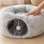 Hand pressing the long-pile plush of the donut cat tunnel bed showing the soft cushion