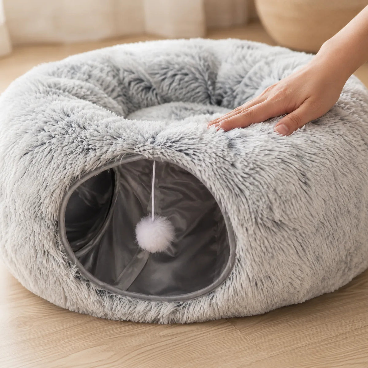 Hand pressing the long-pile plush of the donut cat tunnel bed showing the soft cushion
