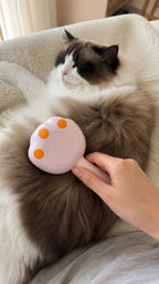 Cordless pink steam brush grooming a relaxed cat on the couch