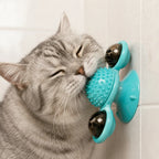 Cat rubbing its cheek on the windmill toy's textured brush ball mounted on a tiled wall