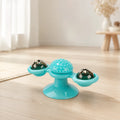 Teal windmill cat toy with suction cup base, spiky dental brush center and two spinning treat balls